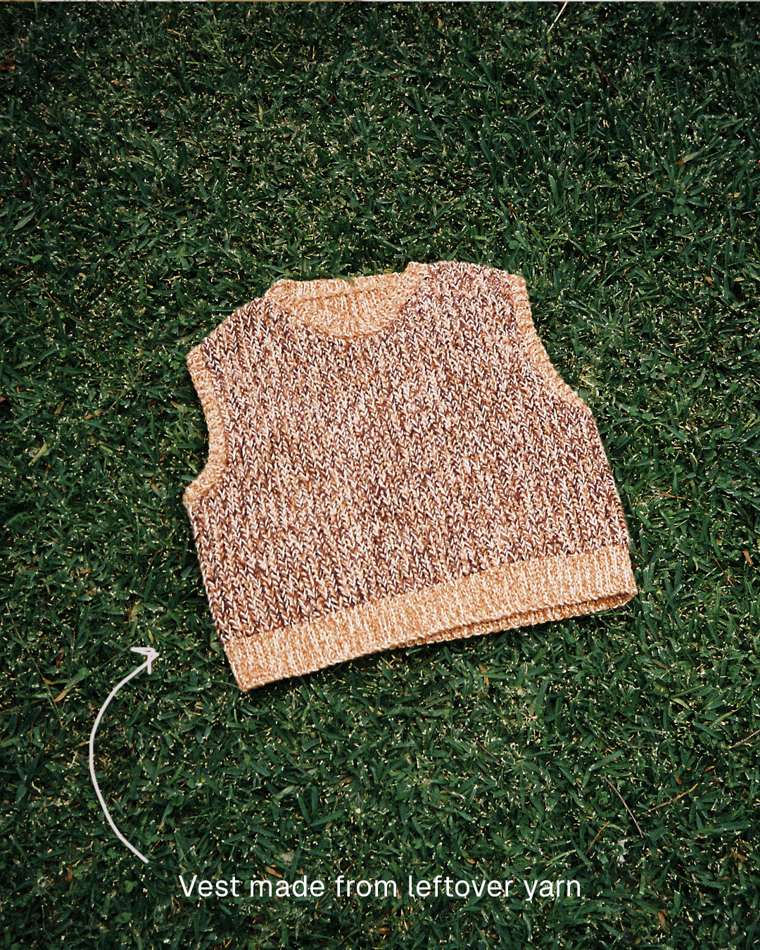 Beige vest crocheted from leftover yarn, laid on grass